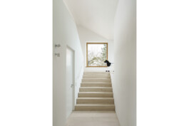 Blick in den offenen Treppenraum ins DAchgeschoss mit großem Fenster auf dem Treppenabsatz. Holzboden und Holzbelag auf der treppe