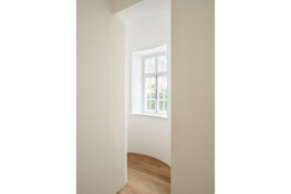 Blick in das ehemalige Treppenhaus mit Rundung und historischem Fenster. Denkmalgeschütze Substanz