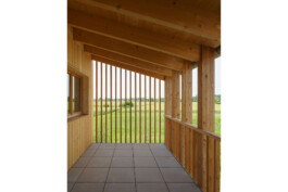 offener Laubengang mit Blick in die freie Landschaft durch Holzlamellen