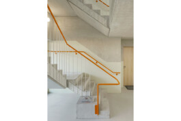 Treppenhaus in Beton mit farbigem Handlauf in orange