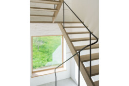 Ausblick aus dem sanierten und umgebauten Bauernhaus vom Obergeschoss auf die freie Landschaft mit der schlichten Holztreppe und deren elegantem MEtallgeländer im Vordergrund