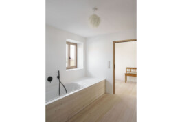 Badsituation mit eingebauter Badewannein Koreanplatte und Lärchenverkleidung. Holzdielenboden Lärche