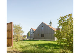 Ansicht des Hofensembles von Norden mit Kirche im HIntergrund,vorvergraute Holzverschalung
